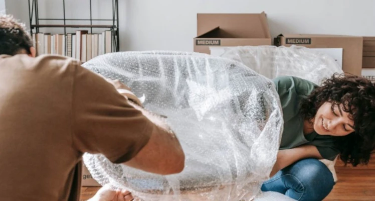 A smiling couple packing and wrapping up furniture